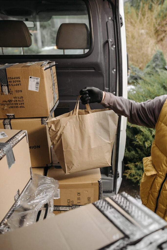 A courier handling packages and paper bags in a van for delivery service.